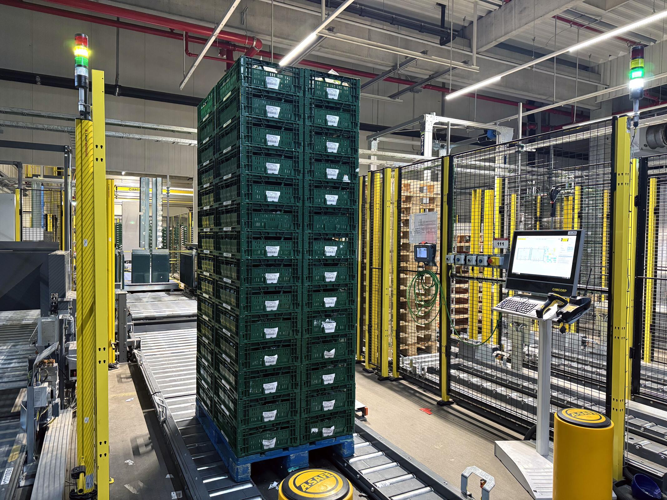 Cimcorp software workstation at Netto's Coswig logistics center, with a fully stacked pallet on the conveyor and empty pallets staged nearby.