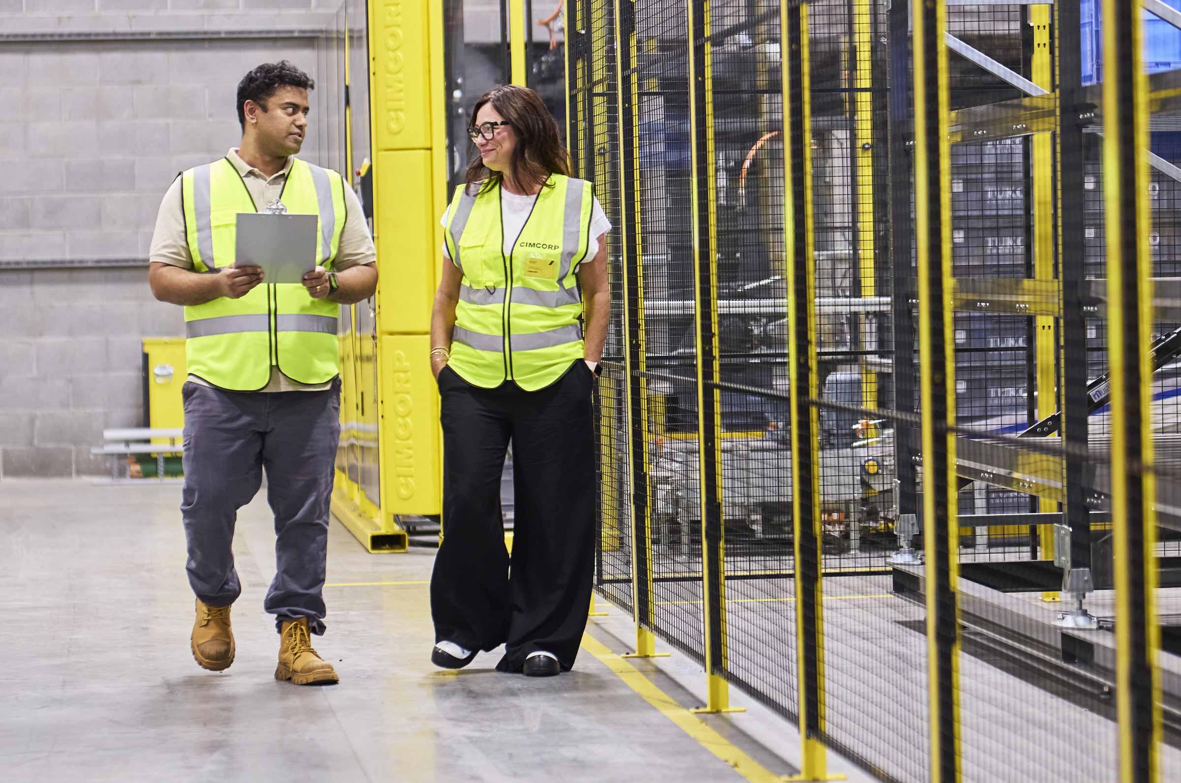 Cimcorp colleagues walking through the automated warehouse aisle